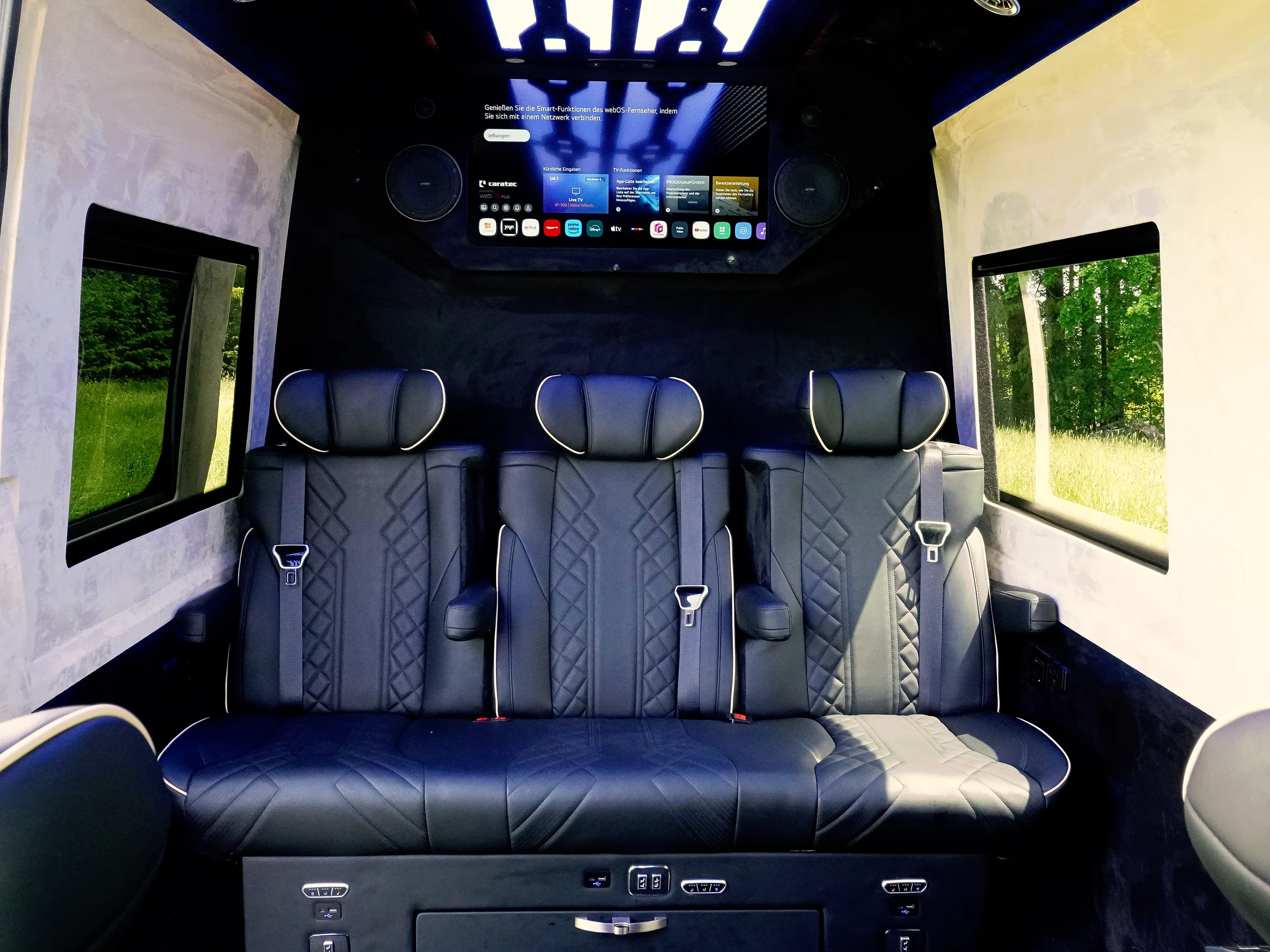 Bildschirm und Sitzbank im Fond eines Busmacher VIP-Busses